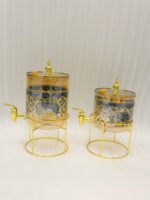 Luxury amber glass beverage dispenser with intricate blue pattern on a decorative gold metal stand