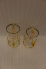 Two luxury clear glass beverage dispensers with gold deer lid handles and matching metallic stands on a marble countertop