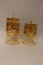 Amber tinted glass beverage dispenser with intricate Islamic mosque gold pattern on a metal stand.