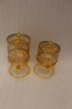 Amber tinted glass beverage dispenser with intricate Islamic mosque gold pattern on a metal stand.