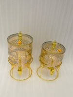 Amber tinted glass beverage dispenser with intricate Islamic mosque gold pattern on a metal stand.