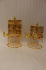 Amber tinted glass beverage dispenser with intricate Islamic mosque gold pattern on a metal stand.