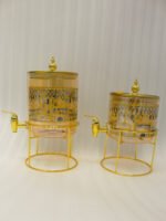 Amber tinted glass beverage dispenser with intricate Islamic mosque gold pattern on a metal stand.
