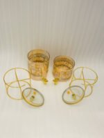 Amber tinted glass beverage dispenser with intricate Islamic mosque gold pattern on a metal stand.