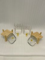 Clear floral patterned glass beverage dispenser with a gold spigot set on a modern wooden stand