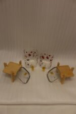Two strawberry pattern glass drink dispensers with gold spigots set on wooden stands in a bright kitchen context.