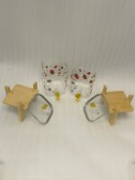 Two strawberry pattern glass drink dispensers with gold spigots set on wooden stands in a bright kitchen context.