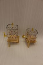 Two square glass beverage dispensers with fruit prints, gold spigots, and wooden stands on a kitchen counter