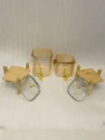 Two amber-shaded glass beverage dispensers with gold spigots, leather handles, and wooden stands on a kitchen counter.