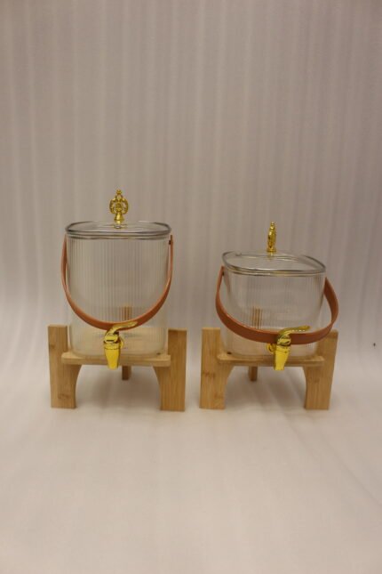 Ribbed glass beverage dispenser with leather carrying handle and gold spigot set on a wooden stand