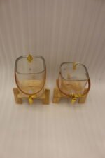 Ribbed glass beverage dispenser with leather carrying handle and gold spigot set on a wooden stand