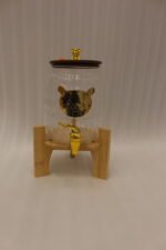 3.6-liter clear glass drink dispenser featuring a gold bear face design, gold spigot, and sturdy wooden stand set on a kitchen counter