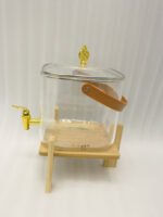 6.5-liter clear glass beverage dispenser with a gold spigot set on a raised wooden stand on a marble countertop