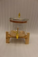 6.5-liter clear glass beverage dispenser with a gold spigot set on a raised wooden stand on a marble countertop