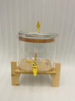 6.5-liter clear glass beverage dispenser with a gold spigot set on a raised wooden stand on a marble countertop