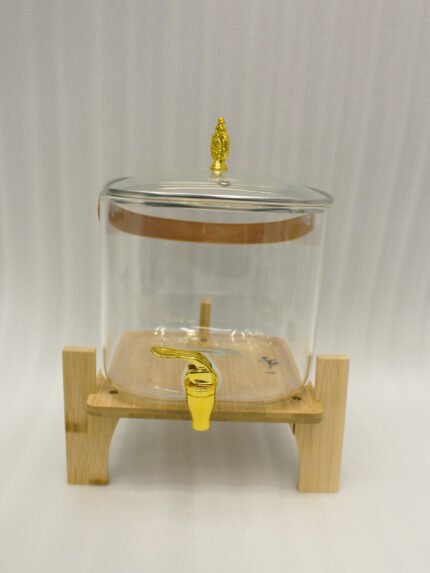 6.5-liter clear glass beverage dispenser with a gold spigot set on a raised wooden stand on a marble countertop