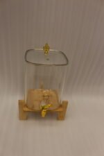 Clear 9.5L glass beverage dispenser with gold spigot on a wooden stand on a white marble countertop