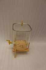 Clear 9.5L glass beverage dispenser with gold spigot on a wooden stand on a white marble countertop