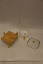 Clear 9.5L glass beverage dispenser with gold spigot on a wooden stand on a white marble countertop