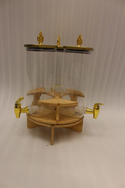 Triple glass beverage dispenser set featuring gold spigots, gold decorative lids, and a wooden rotating stand on a kitchen countertop.