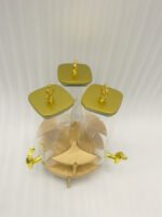 Triple glass beverage dispenser set featuring gold spigots, gold decorative lids, and a wooden rotating stand on a kitchen countertop.