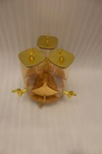 3-piece amber shaded glass beverage dispenser set with gold spigots on a wooden stand