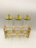 Triple clear acrylic beverage dispenser set on a wooden stand with gold spigots and decorative finial tops on a kitchen counter