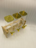 Triple clear acrylic beverage dispenser set on a wooden stand with gold spigots and decorative finial tops on a kitchen counter