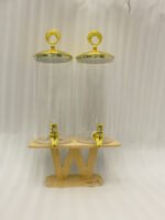 Two tall clear glass drink dispensers with gold spigots and circular gold finial lids resting on a wooden W-shaped stand.