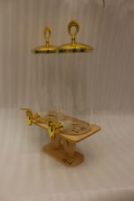 Two tall clear glass drink dispensers with gold spigots and circular gold finial lids resting on a wooden W-shaped stand.