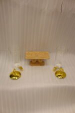 Two tall clear glass drink dispensers with gold spigots and circular gold finial lids resting on a wooden W-shaped stand.
