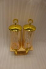 Dual 3.3L amber shaded glass beverage dispensers with gold lids and spigots on a W-shaped wooden stand sitting on a modern kitchen counter.