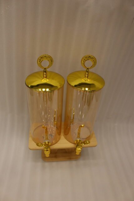 Dual 3.3L amber shaded glass beverage dispensers with gold lids and spigots on a W-shaped wooden stand sitting on a modern kitchen counter.