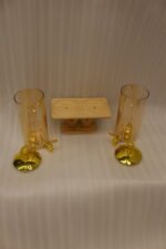Dual 3.3L amber shaded glass beverage dispensers with gold lids and spigots on a W-shaped wooden stand sitting on a modern kitchen counter.