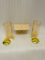 Dual 3.3L amber shaded glass beverage dispensers with gold lids and spigots on a W-shaped wooden stand sitting on a modern kitchen counter.