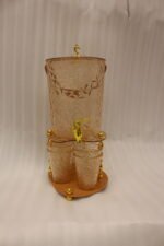 Elegant pink acrylic beverage dispenser with gold swan finial, gold spigot, stand, and 6 matching diamond-cut glasses.