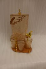 Elegant pink acrylic beverage dispenser with gold swan finial, gold spigot, stand, and 6 matching diamond-cut glasses.