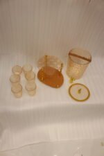 Elegant pink acrylic beverage dispenser with gold swan finial, gold spigot, stand, and 6 matching diamond-cut glasses.