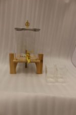4.2L clear glass beverage dispenser with a gold spigot, gold lid handle, natural wooden stand, and 4 drinking glasses on a kitchen island.