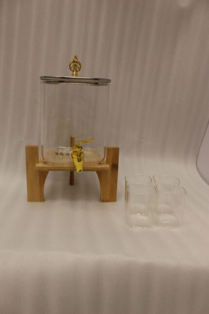 4.2L clear glass beverage dispenser with a gold spigot, gold lid handle, natural wooden stand, and 4 drinking glasses on a kitchen island.