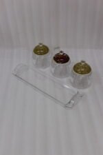 3-piece clear acrylic jar set with patterned dome lids, clear spoons, and serving tray on a kitchen countertop