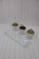 3-piece clear acrylic jar set with patterned dome lids, clear spoons, and serving tray on a kitchen countertop