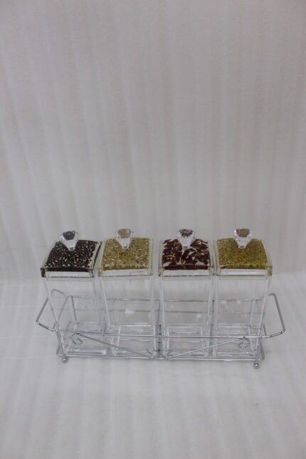 4-piece clear acrylic spice jar set with decorative crystal knob lids arranged in a metal chrome holder on a kitchen countertop