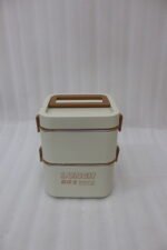 Cream and brown 2-in-1 double-layer portable lunch box with handle sitting on a kitchen counter