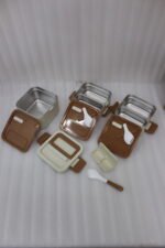 Cream and brown 3-tier stackable stainless steel lunch box with carrying handle on a kitchen counter