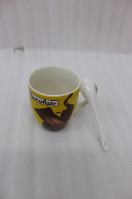 Yellow ceramic chocolate mug with handle holding a matching white spoon on a granite countertop
