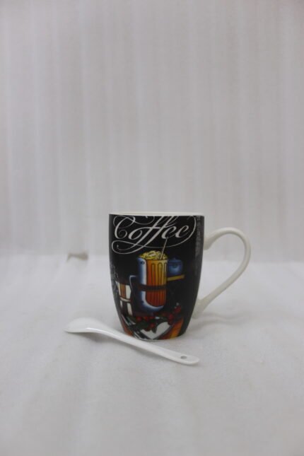 Black ceramic mug printed with vintage Coffee artwork resting on a granite kitchen counter alongside a white ceramic spoon.