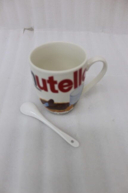 White ceramic coffee mug printed with Nutella hazelnut spread logo and toast graphics resting on a kitchen counter next to a white spoon.