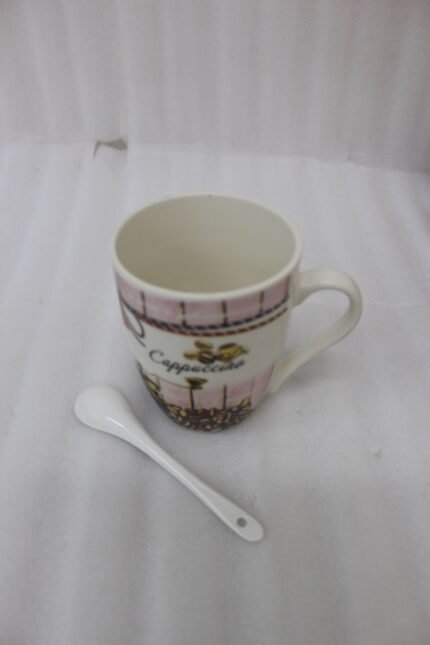 Vintage-style ceramic cappuccino mug with printed coffee beans and vintage coffee grinder, placed next to a small white ceramic spoon on a granite countertop.