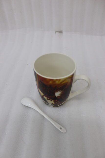 Ceramic mug featuring a full-wrap printed coffee bean and espresso graphic sitting on a kitchen counter next to a matching white ceramic spoon.